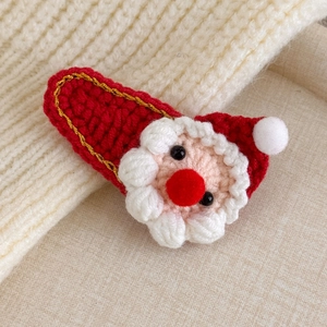 Detailed close-up of a handmade knitted Santa Claus hair clip with soft wool texture