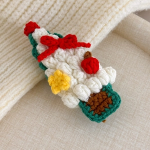 Detail of a handmade white crochet Christmas tree hair clip with red bow and yellow star