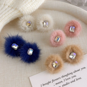 Winter plush ball earrings with crystal accents in four colors on a white display