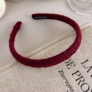 Detailed close-up of dark burgundy knitted headband with a handmade label on fabric