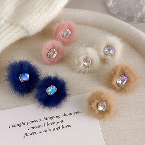 Close-up of fluffy velvet pompom earrings with rectangular gems in multiple autumn colors