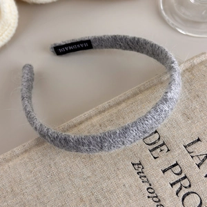 Detailed close-up of a grey knitted headband with a black handmade woven label tag