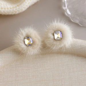 Close-up of fluffy cream faux mink fur stud earrings with iridescent square crystal