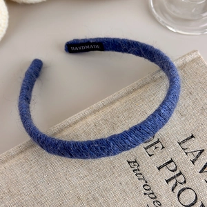 Detail of navy knit headband with handmade label on rustic book background
