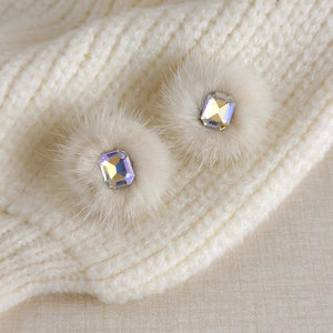Detailed macro view of square AB crystal earrings with ivory faux fur trim on knit fabric