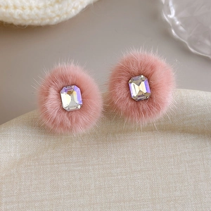 Close-up of pink fur stud earrings with rectangular crystal stones for winter style