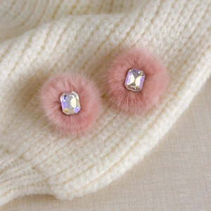 Close-up of pink fluffy earrings with rectangular iridescent rhinestone on white knit