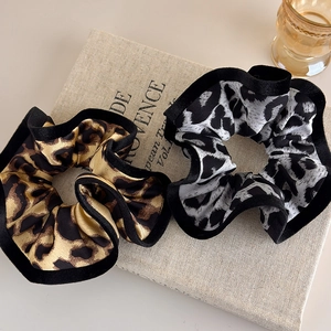 Retro leopard print scrunchies with black velvet edges on a vintage book backdrop