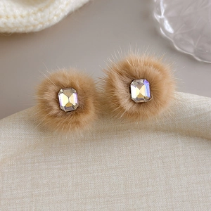 Close-up of brown fur pom-pom earrings with rectangular rainbow crystal stones