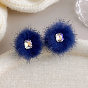 Detailed view of dark blue pom-pom earrings featuring a sparkling square-cut rhinestone
