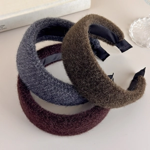 Close-up of three plush padded headbands in grey, coffee, and burgundy faux fur texture