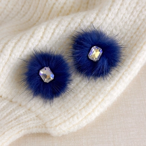 Close-up of deep blue faux fur earrings featuring a polished rectangular crystal accent