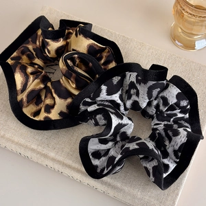 Detailed view of leopard print scrunchies with elegant ruffled edges and satin texture