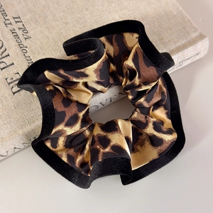Close-up of leopard print hair scrunchie with black velvet trim on a vintage book