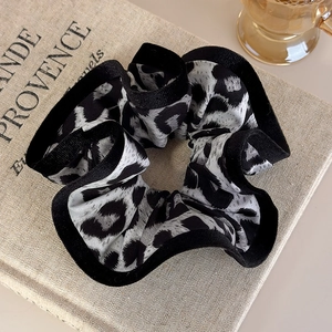 Close-up of leopard print scrunchie with black hemmed edges on vintage book background