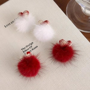 Détail de pinces à cheveux pompons avec cœurs en tissu à carreaux rouges sur un vieux livre