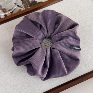 Détail d'un chouchou en velours côtelé violet foncé avec texture côtelée douce et élégante