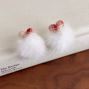Détail de boucles d'oreilles pompons blancs avec charmes de cœur à carreaux rouges
