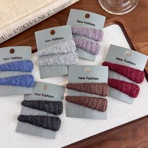 Set of six colorful knit wool triangle hair clips neatly arranged on a rustic tray