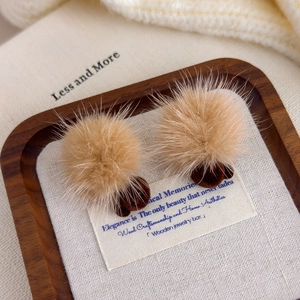 Detail of fuzzy brown plush pom-pom bear earrings on a rustic tray for autumn