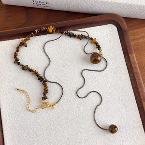 Detail of irregular tiger eye stone beads combined with a sleek golden snake chain link