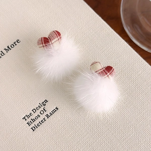 Gros plan sur les boucles d'oreilles pompon blanches avec des cœurs en tissu à carreaux