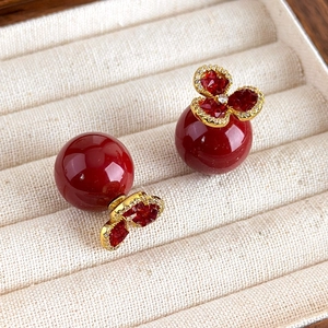 Detailed close-up of red zircon flower stud earrings with a pearl backing on a jewelry tray