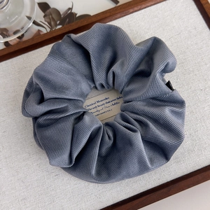 Gros plan d'un chouchou en tissu sergé bleu-gris sur un fond de texture lin