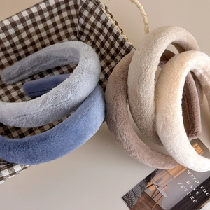 Détail de cinq serre-têtes moelleux en fausse fourrure de lapin dans un panier tissé
