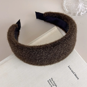 Detail view of the plush brown wide headband with soft texture on a white book