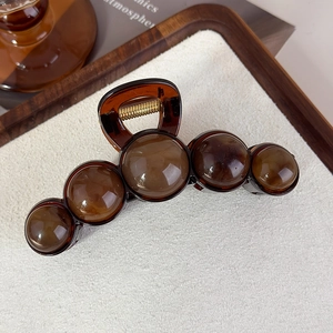 Vue détaillée de la pince à cheveux ambre avec boules en résine et ressort doré