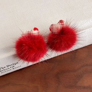 Détail macro des boucles d'oreilles pompon rouge avec cœurs en tissu à carreaux