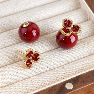 Elegant red flower pearl stud earrings with zircon petals and gold needles on fabric