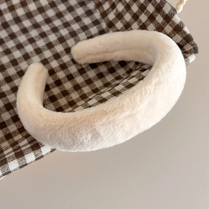Gros plan sur un serre-tête en fausse fourrure de lapin blanc crème à texture douce