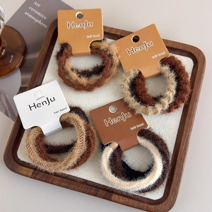 Set of thick plush hair scrunchies in warm brown and beige colors on a display card