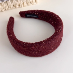 Detail of burgundy wool headband with golden glitter thread and handmade label