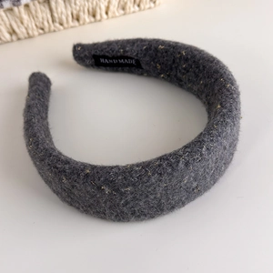 Detail of dark gray wool texture with gold metallic threads and a handmade fabric label