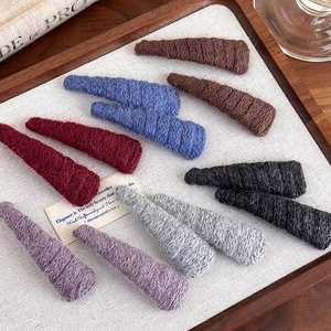 Detail of colorful hand-knitted triangular hair clips in vintage tones on a wooden tray