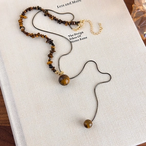Detail of irregular tiger eye stone necklace with black snake chain and gold clasp