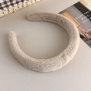 Gros plan sur la texture pelucheuse du serre-tête beige en fausse fourrure de lapin