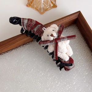 Détail de la grande pince à cheveux à carreaux avec ours en peluche blanc sur plateau