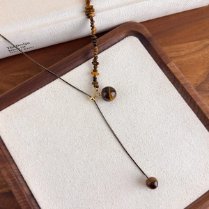 Macro shot of tiger eye stone beaded necklace with Y-shape adjustable design on white velvet