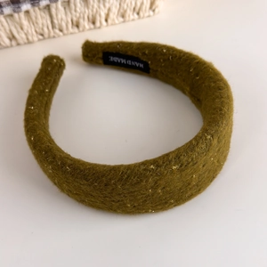 Detailed texture of olive green wool headband with gold silk threads and handmade label