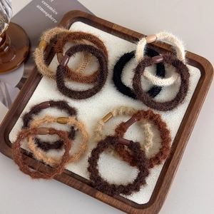 Close-up of plush velvet hair scrunchies in earth tones on a soft display tray
