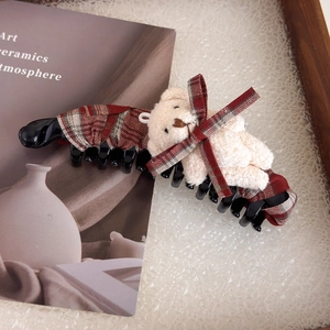 Détail d'une pince banane à carreaux marron avec un joli petit ours en peluche beige
