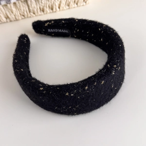 Detail view of handmade black tweed headband with gold silk threading and interior label