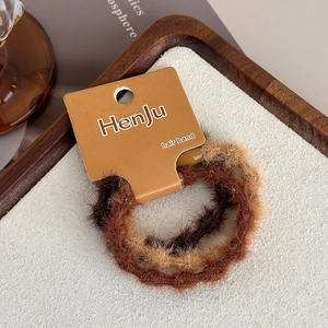 Detailed view of three plush elastic hair bands in warm brown tones on a display tray