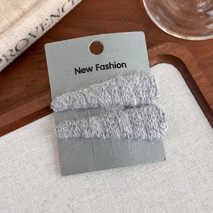 Macro shot of grey knitted wool triangle hair clips on a decorative display card