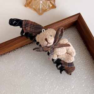 Détail d'un ours en peluche avec nœud à carreaux sur une grande pince banane