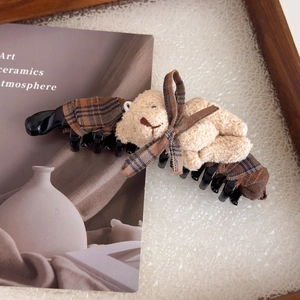 Détail d'une pince à cheveux à nœud écossais marron avec un petit ours en peluche